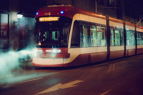 A modern streetcar operating at night in downtown Toronto with an illuminated destination sign and city lights, showcasing Toronto’s public transportation system.